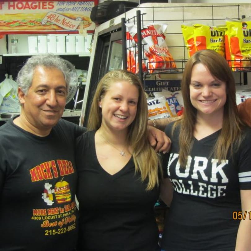 Three smiling Koch's Deli employees, two women and one man, stand together in the deli.