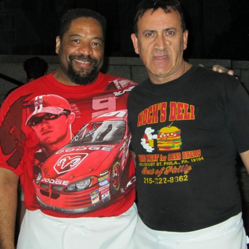 Two men, one in a Koch's Deli t-shirt, smile at the camera.